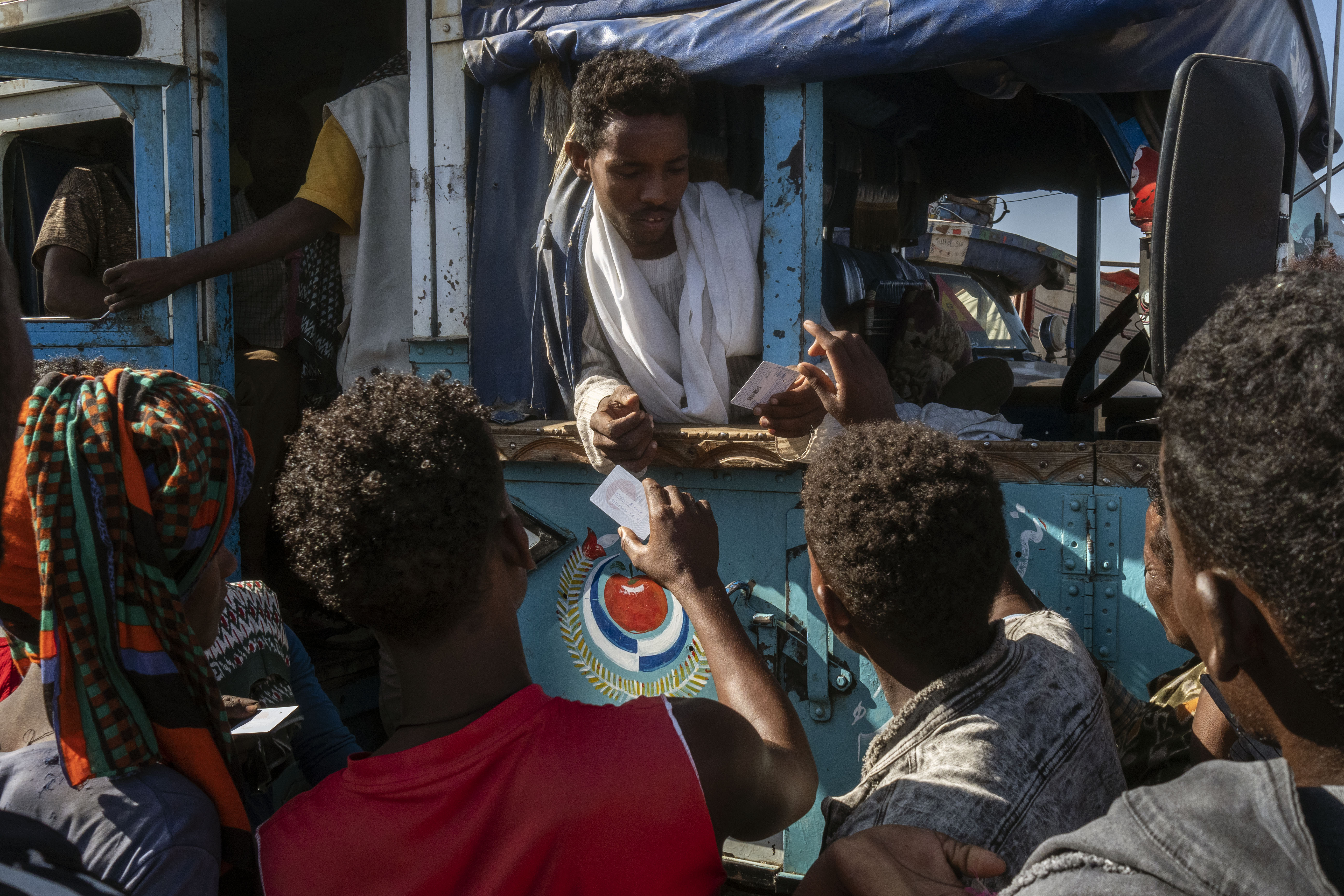 Des réfugiés éthiopiens se préparent à monter dans les bus qui les transféreront du camp de transit d'Al Hashaba au camp de réfugiés d'Um Rakuba. Soudan, 2020 