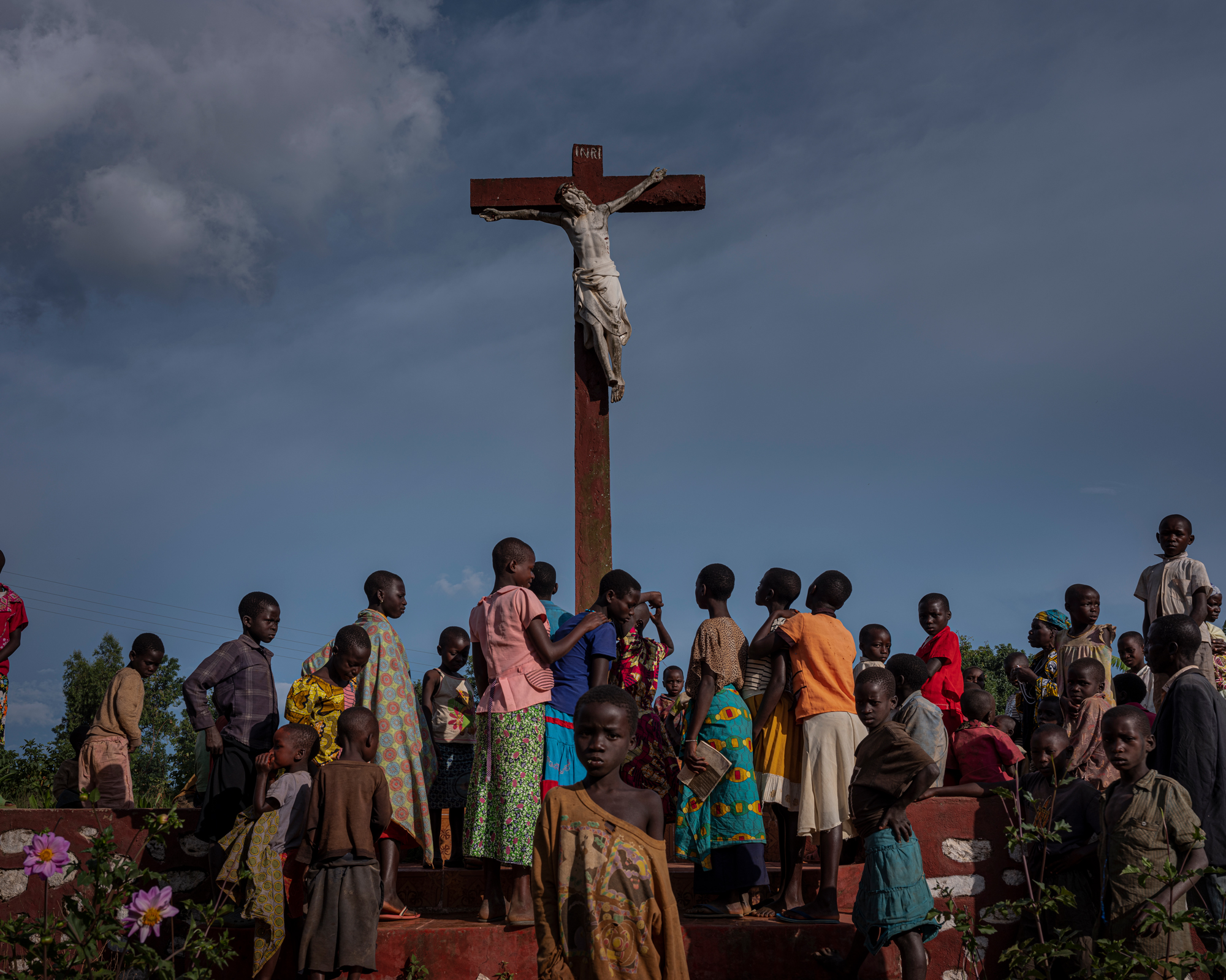People gather near a large cross by the main road in Drodro.