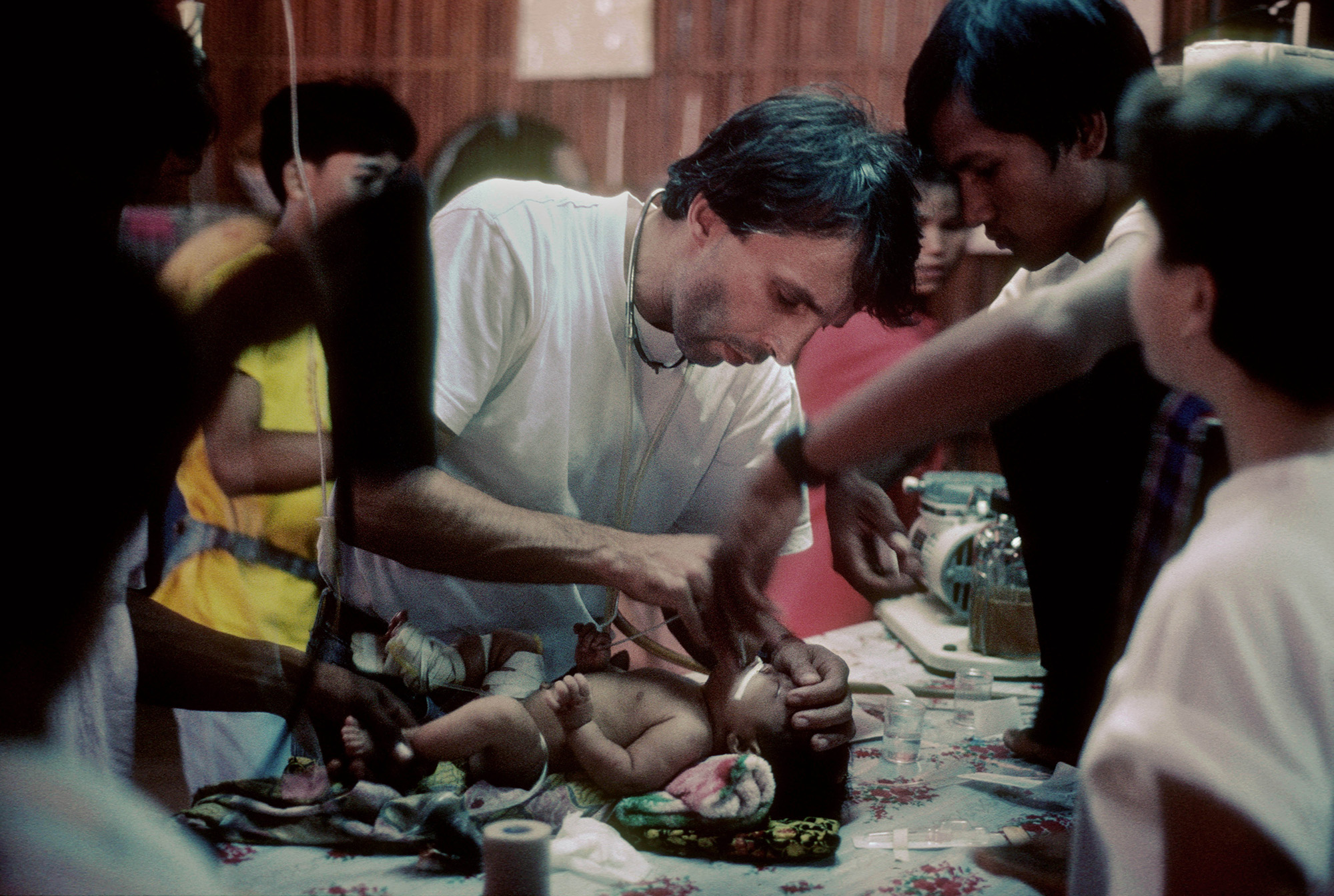 Yves Coyette, an MSF doctor, treats a sick baby in Khao I Dang refugee camp. Thailand 1984 