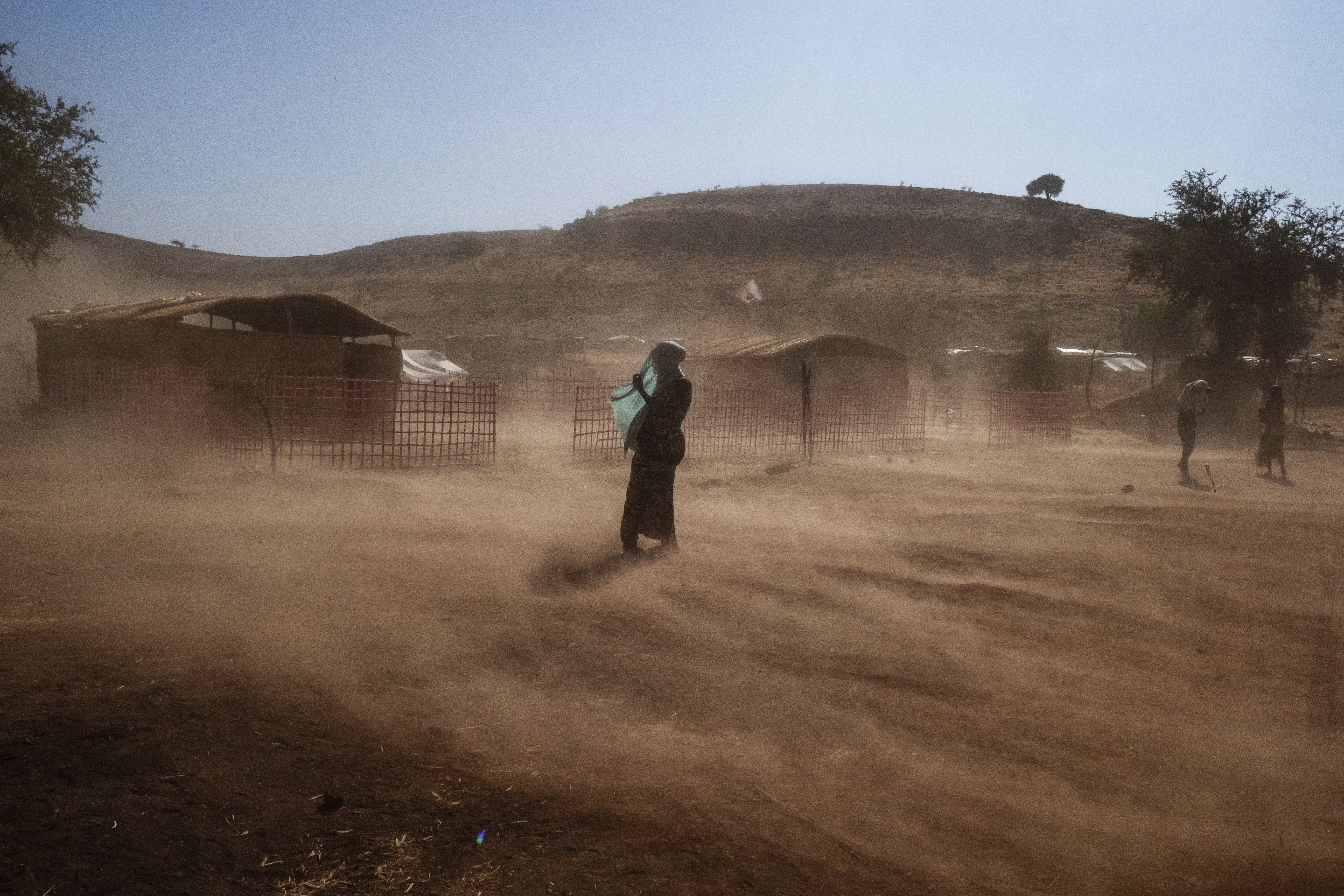 A woman shields her face against the dust in Um Rakuba camp. 