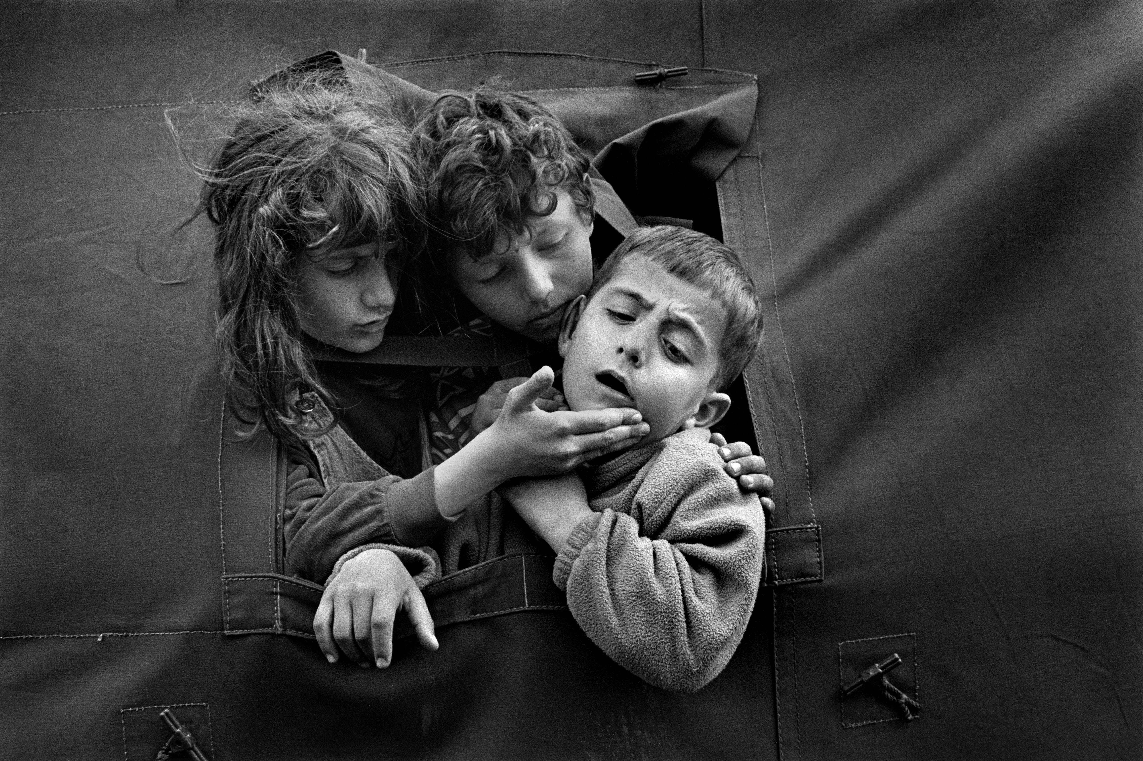 Children comfort their injured friend in Stenkovac refugee camp. Macedonia 1999 